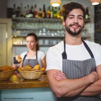 smiling-waiter-standing-with-arms-crossed-in-cafa-c